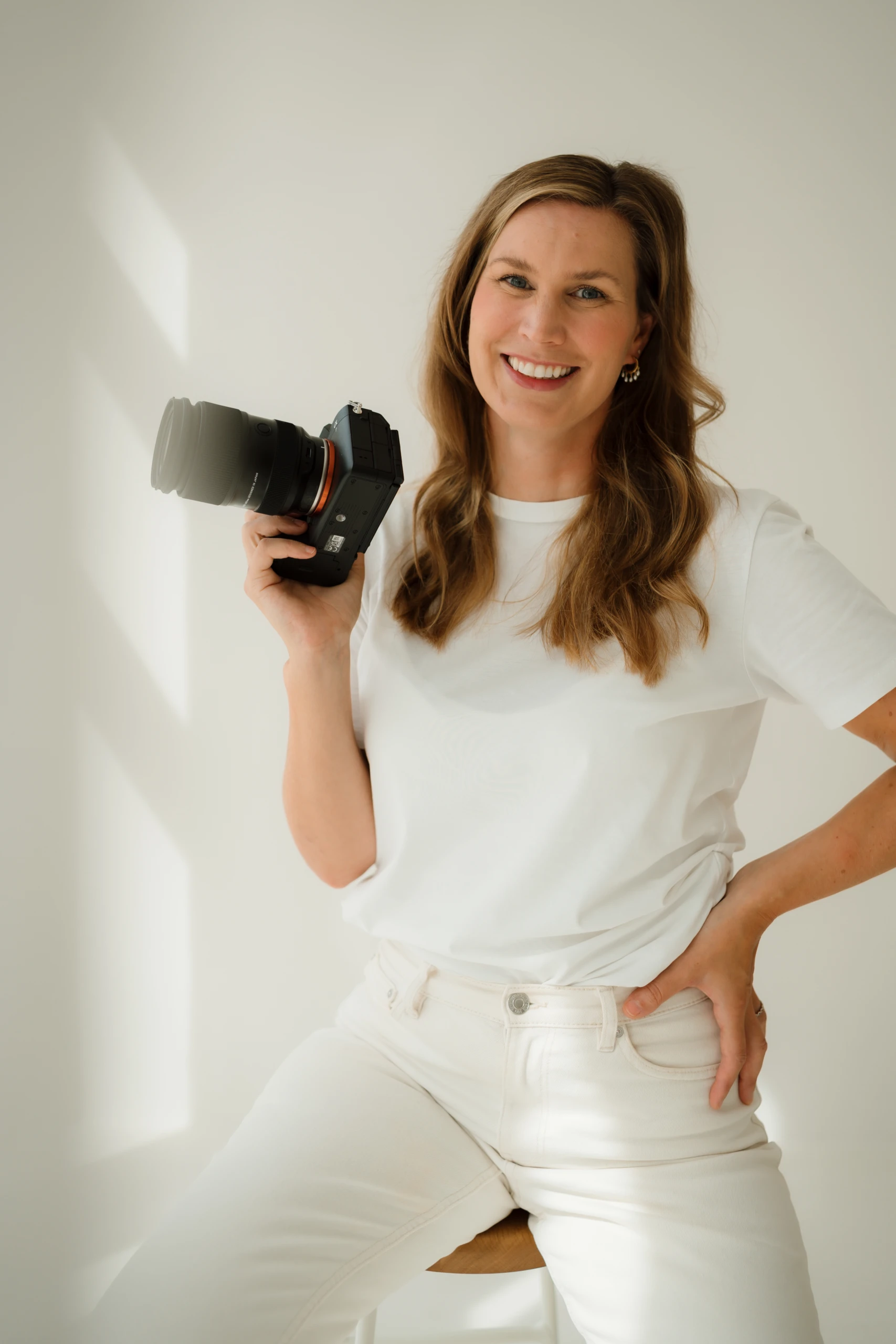 Jana von Fotoatelier Fuchs lächelt mit ihrer Kamera in der Hand in die Kamera.